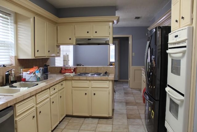 9222 Chesney Downs Dr, Houston, TX 77083 - kitchen featuring cream cabinetry, tile countertops, appliances with stainless steel finishes, and a peninsula