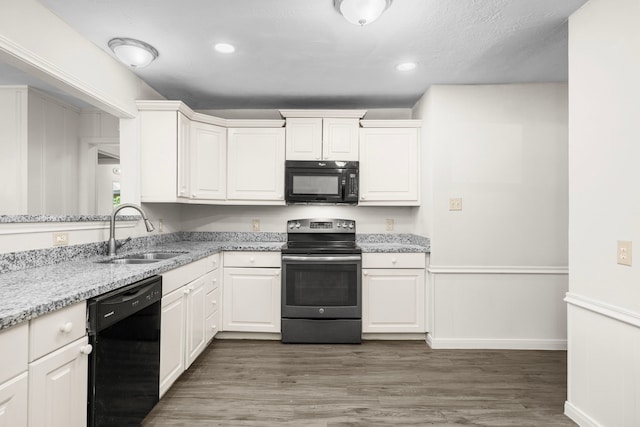 5006 Live Oak Dr, Texas City, TX 77591 - kitchen with white cabinetry, a sink, black appliances, and wood finished floors
