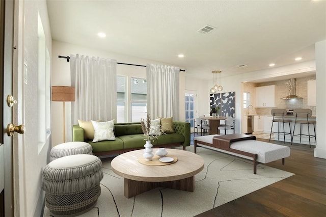 living room with recessed lighting, visible vents, and wood finished floors