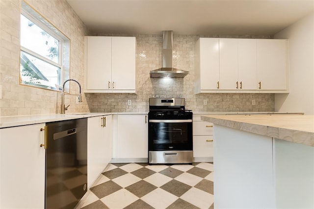 kitchen featuring wall chimney range hood, appliances with stainless steel finishes, a sink, and light countertops