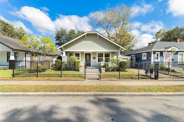bungalow with covered porch, a fenced front yard, and a front lawn