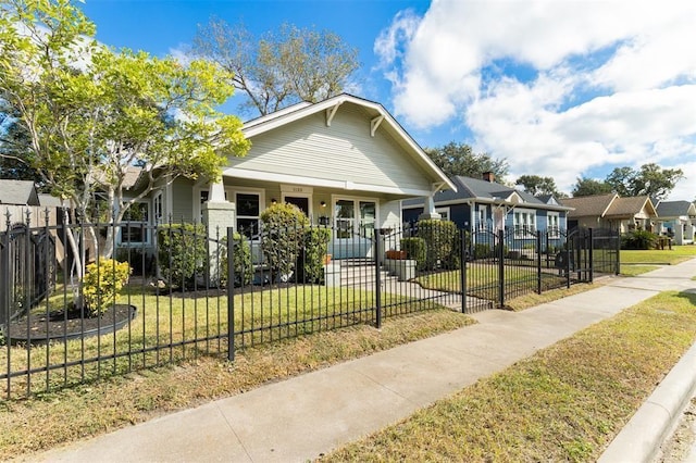bungalow featuring a porch, a residential view, a fenced front yard, and a front yard