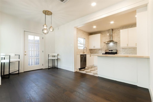 kitchen with wall chimney range hood, dark wood-style flooring, light countertops, stainless steel appliances, and white cabinetry
