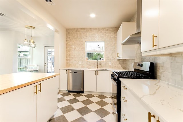 kitchen with appliances with stainless steel finishes, a sink, white cabinetry, decorative backsplash, and light floors