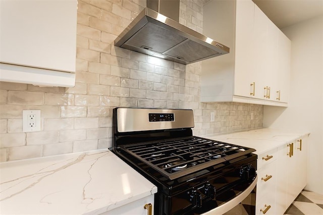 kitchen with gas stove, light stone countertops, wall chimney range hood, and white cabinetry