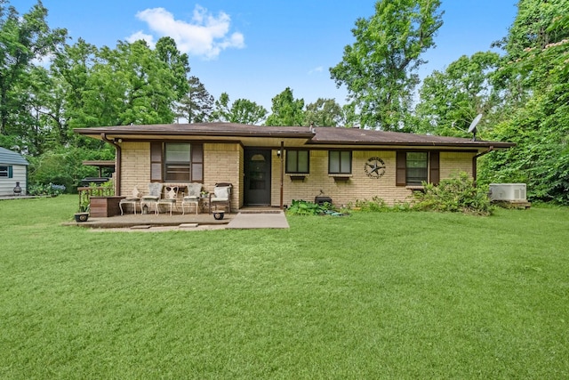 view of front of house with brick siding, cooling unit, and a front yard