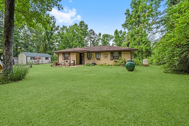 rear view of house with a lawn, an outbuilding, a patio area, brick siding, and a storage unit