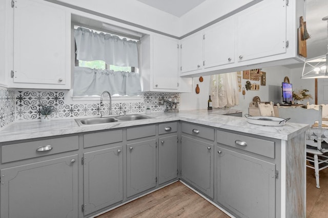 kitchen featuring a sink, light countertops, gray cabinetry, and light wood-style flooring