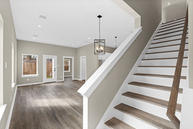 stairway with a notable chandelier, recessed lighting, baseboards, wood finished floors, and visible vents