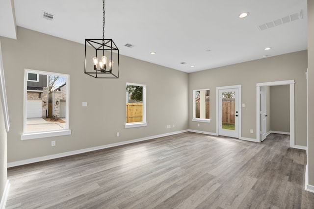 unfurnished dining area with visible vents, wood finished floors, and an inviting chandelier