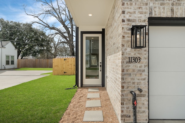 entrance to property featuring a lawn and fence