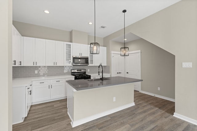 kitchen featuring wood finished floors, white cabinets, tasteful backsplash, a sink, and stainless steel appliances