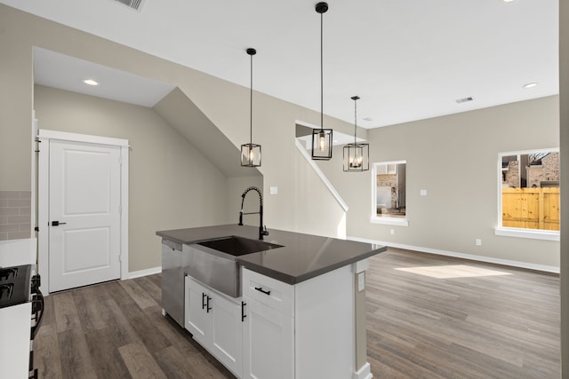 kitchen featuring dark countertops, a sink, dishwasher, white cabinetry, and dark wood-style floors
