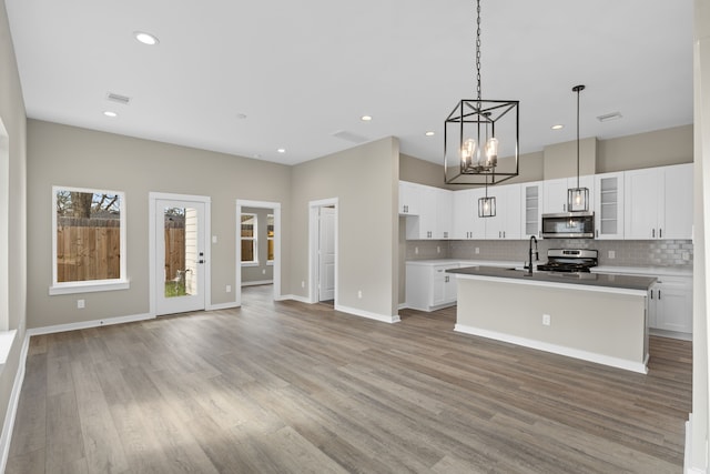 kitchen featuring stainless steel appliances, an inviting chandelier, decorative backsplash, and light wood-type flooring
