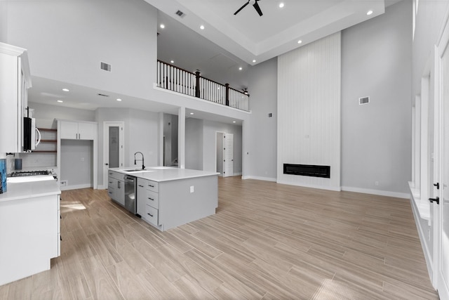 kitchen with visible vents, a sink, light countertops, a high ceiling, and stainless steel appliances