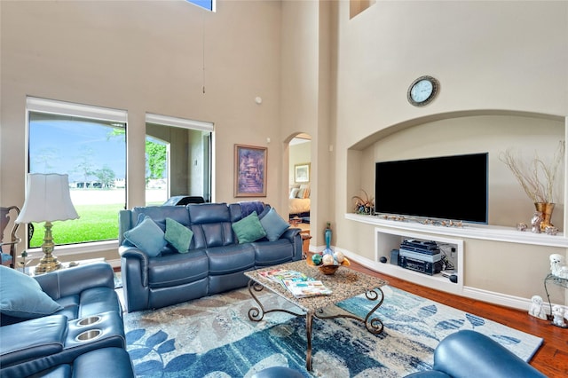 6119 Lofty Ln, Spring, TX 77379 - living room with arched walkways, wood finished floors, a towering ceiling, and baseboards