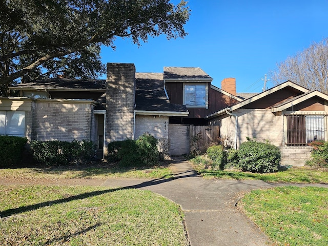 view of front of house featuring brick siding, a front yard, and a chimney