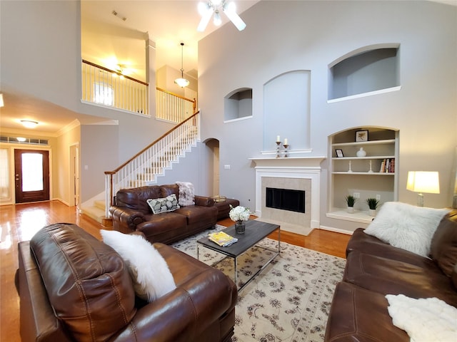 5439 Emerald Pointe Ln, Sugar Land, TX 77479 - living room featuring stairs, wood finished floors, a high ceiling, built in shelves, and a tiled fireplace