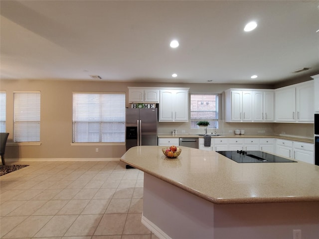 5439 Emerald Pointe Ln, Sugar Land, TX 77479 - kitchen featuring appliances with stainless steel finishes, a center island, white cabinetry, baseboards, and light tile patterned floors