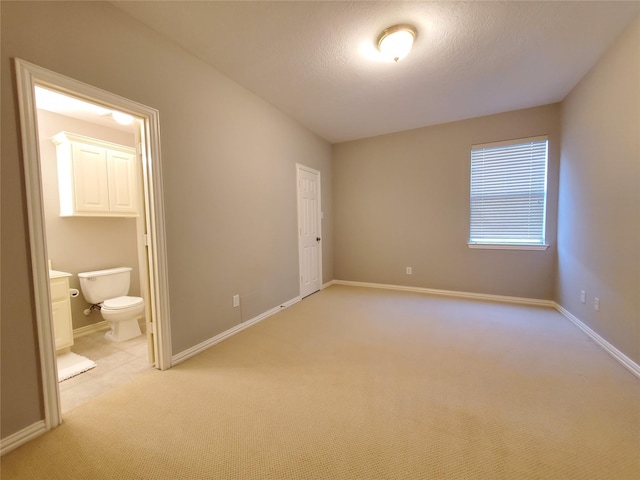 5439 Emerald Pointe Ln, Sugar Land, TX 77479 - unfurnished bedroom featuring baseboards, ensuite bath, and light colored carpet