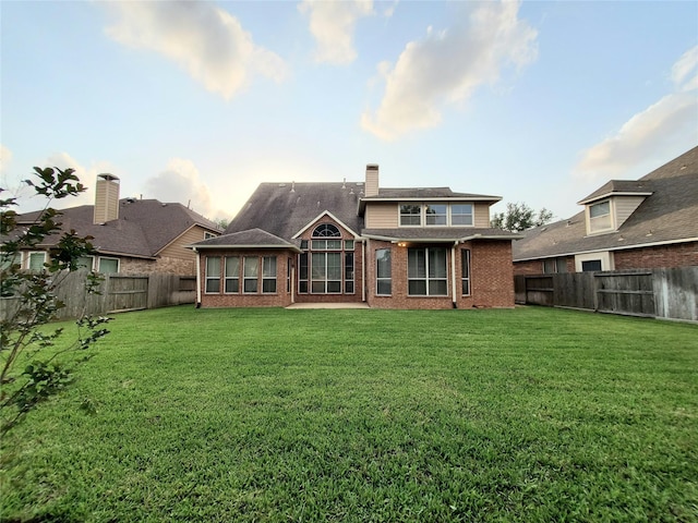 5439 Emerald Pointe Ln, Sugar Land, TX 77479 - back of house with brick siding, a fenced backyard, a yard, and a chimney