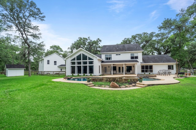 back of house with fence, a yard, a shed, a patio area, and an outbuilding