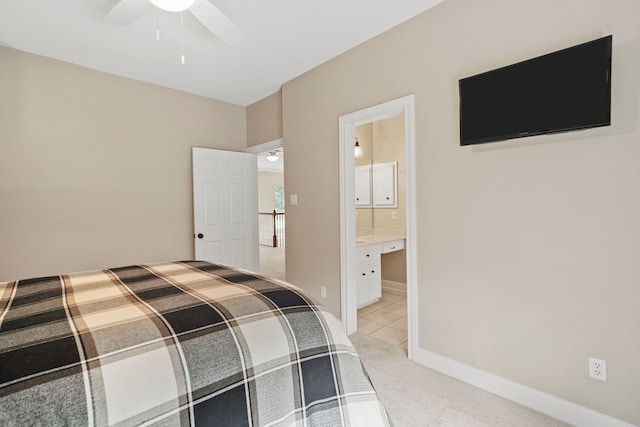 unfurnished bedroom featuring baseboards, ensuite bathroom, light carpet, and ceiling fan