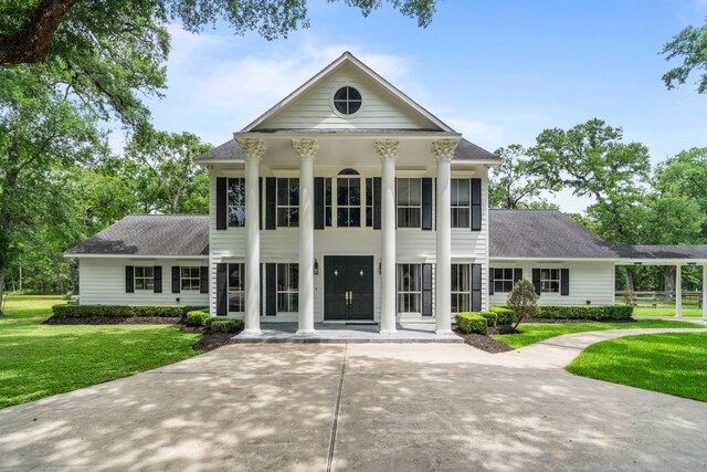 neoclassical / greek revival house with a shingled roof, a front lawn, and covered porch
