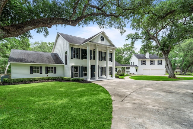 neoclassical home with roof with shingles, concrete driveway, and a front yard