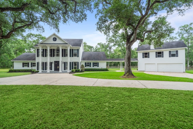 greek revival house with a porch, an attached garage, driveway, and a front lawn