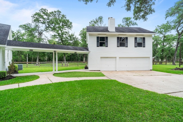 view of front facade with concrete driveway, an attached garage, a chimney, and a front yard
