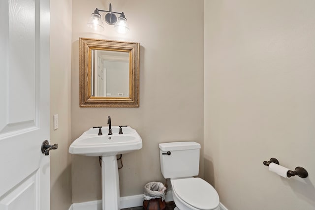 half bathroom featuring baseboards and toilet