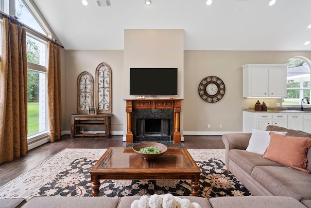 living room featuring recessed lighting, baseboards, dark wood-style floors, and a premium fireplace