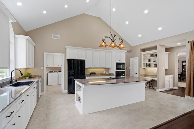 kitchen featuring open shelves, a sink, a center island, washer and clothes dryer, and black appliances