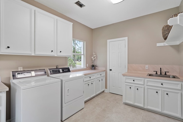 clothes washing area featuring cabinet space, independent washer and dryer, light tile patterned floors, and a sink