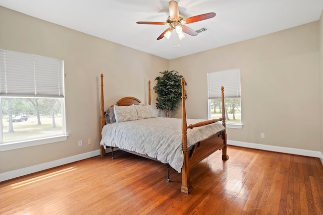 bedroom with a ceiling fan, baseboards, visible vents, and light wood finished floors