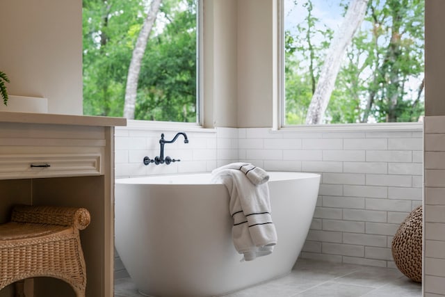 bathroom featuring a freestanding tub, tile walls, tile patterned flooring, and wainscoting