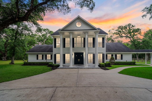 view of front facade featuring roof with shingles, covered porch, a front yard, and concrete driveway