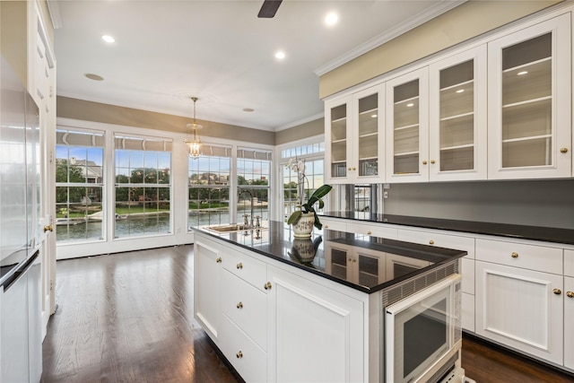 kitchen with a sink, white cabinetry, crown molding, dark countertops, and dark wood-style floors
