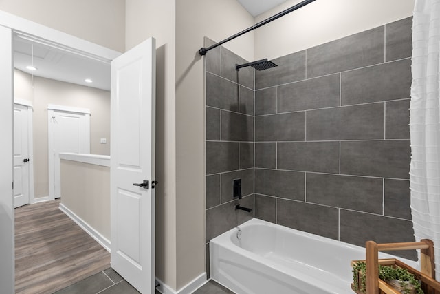 bathroom with baseboards, recessed lighting, wood finished floors, and tub / shower combination