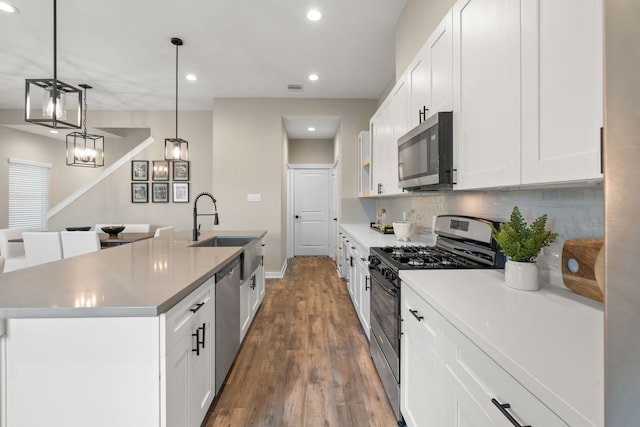 kitchen with an island with sink, white cabinets, stainless steel appliances, recessed lighting, and dark wood-type flooring