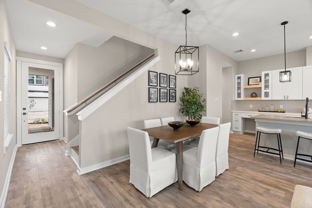 dining room featuring stairs, wood finished floors, baseboards, a chandelier, and recessed lighting