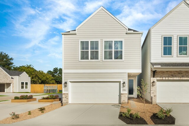 view of front of house with an attached garage, fence, and concrete driveway