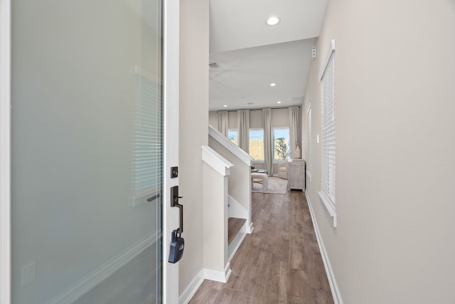 hallway with baseboards, recessed lighting, wood finished floors, and stairway
