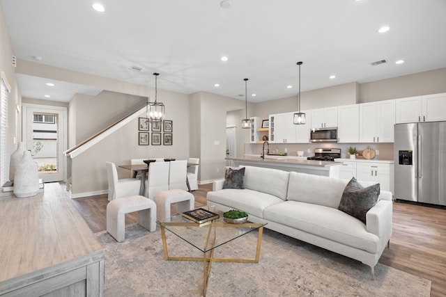 living room with recessed lighting, baseboards, and light wood-style flooring