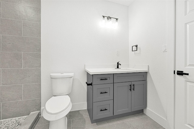 full bath with a tile shower, vanity, tile patterned floors, baseboards, and toilet