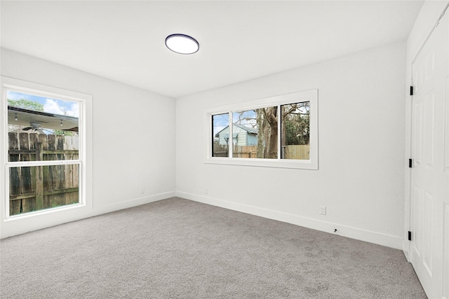 carpeted spare room featuring baseboards and a wealth of natural light