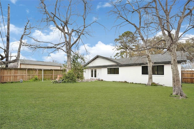 rear view of property featuring a yard, a fenced backyard, and roof with shingles