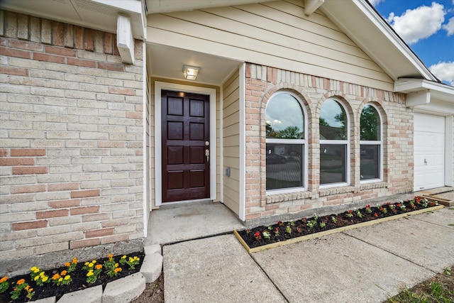 property entrance with an attached garage and brick siding