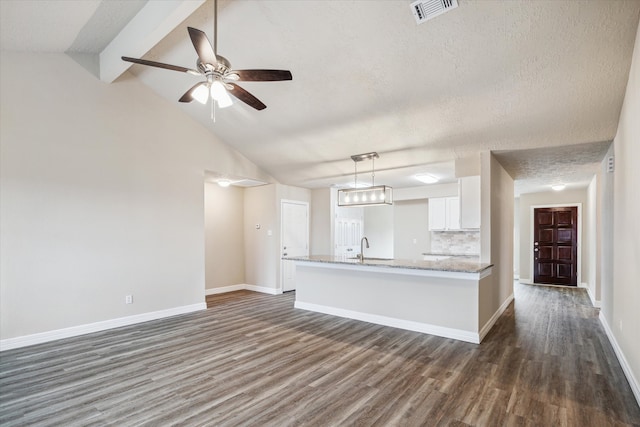 unfurnished living room featuring visible vents, a ceiling fan, dark wood finished floors, and baseboards